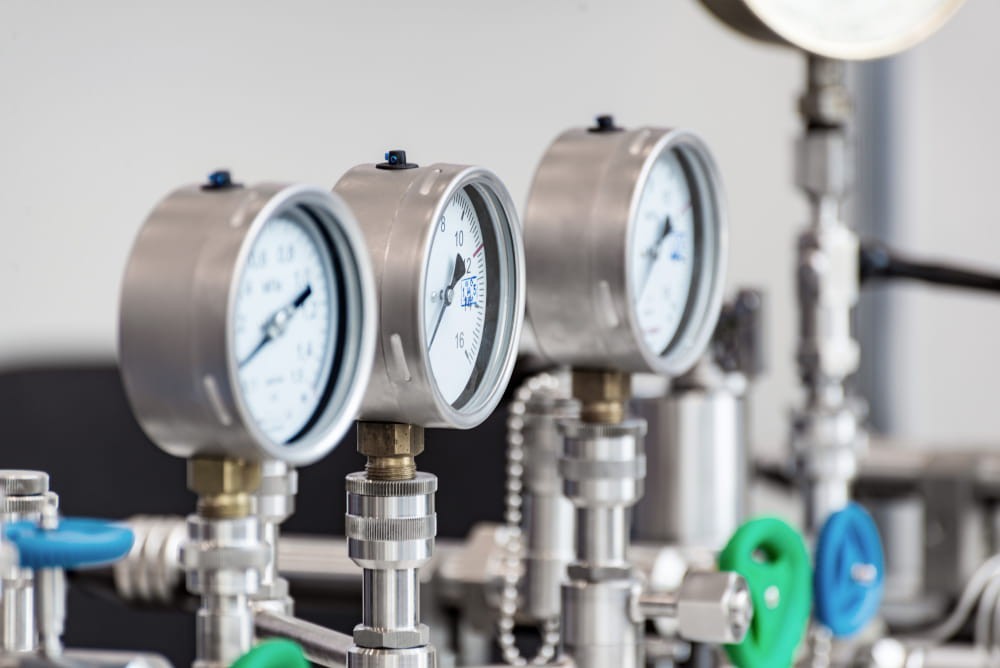Un gruppo di manometri industriali su un impianto di refrigerazione, utilizzati dal tecnico per monitorare pressione e temperatura del sistema.